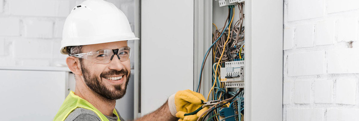 Électricien professionnel souriant devant un tableau électrique – SCH Technics Charleroi
